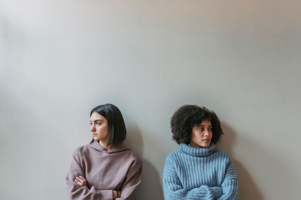 Two people with their arms crossed while facing away from each other