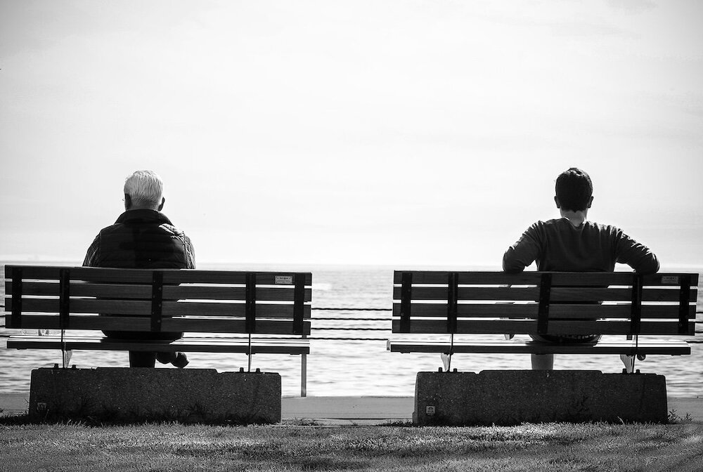Two people sitting on separate benches