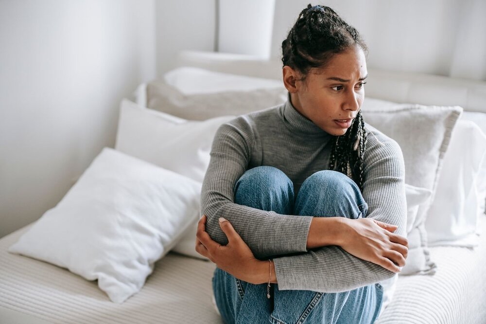 Person sitting with arms wrapped around their legs and looking to the left