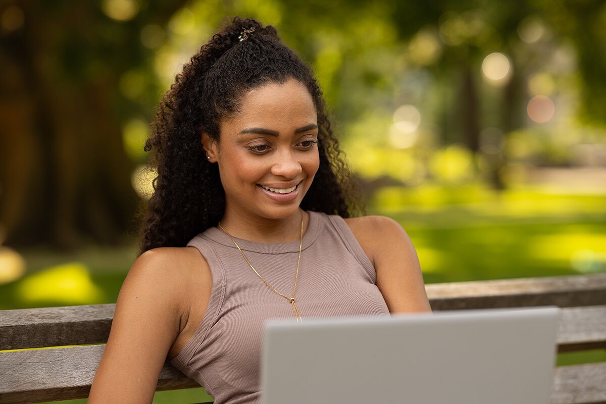 A smiling woman outdoors with a blue sky in the background.