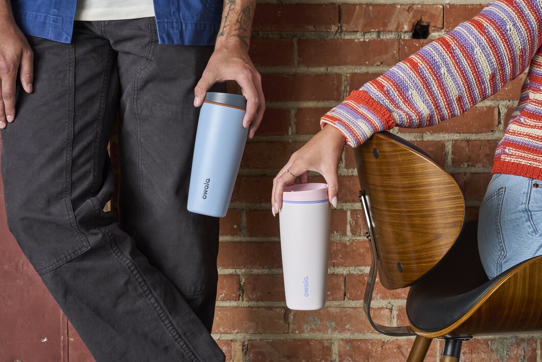 Two people holding blue and pink SmoothSip Slider Coffee Mugs.