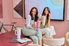 Two girls sitting at a table, laughing while each holding an Owala 40oz tumbler.