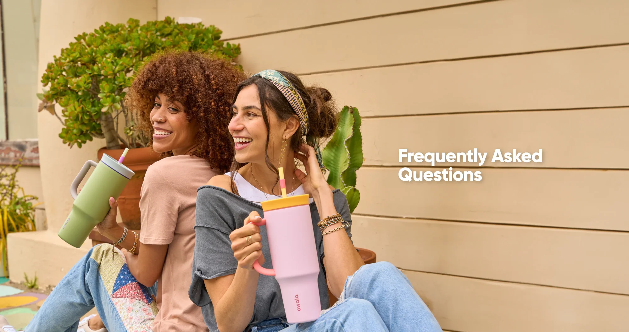 Two women enjoying drinks from pink and green Owala tumblers while relaxing outdoors.