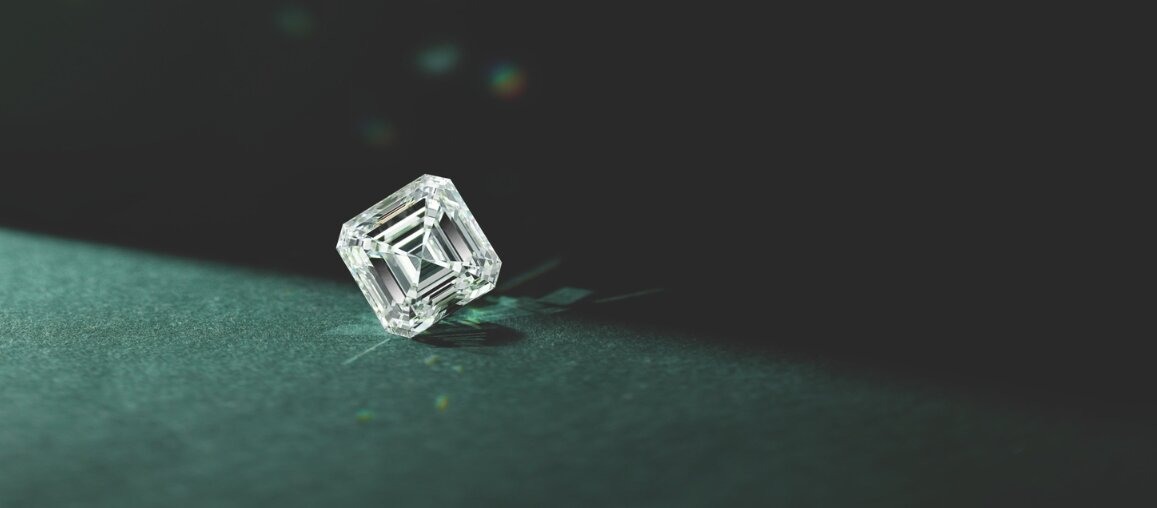 Loose emerald-cut lab-grown diamond displayed on green surface highlighting step-cut clarity and symmetry