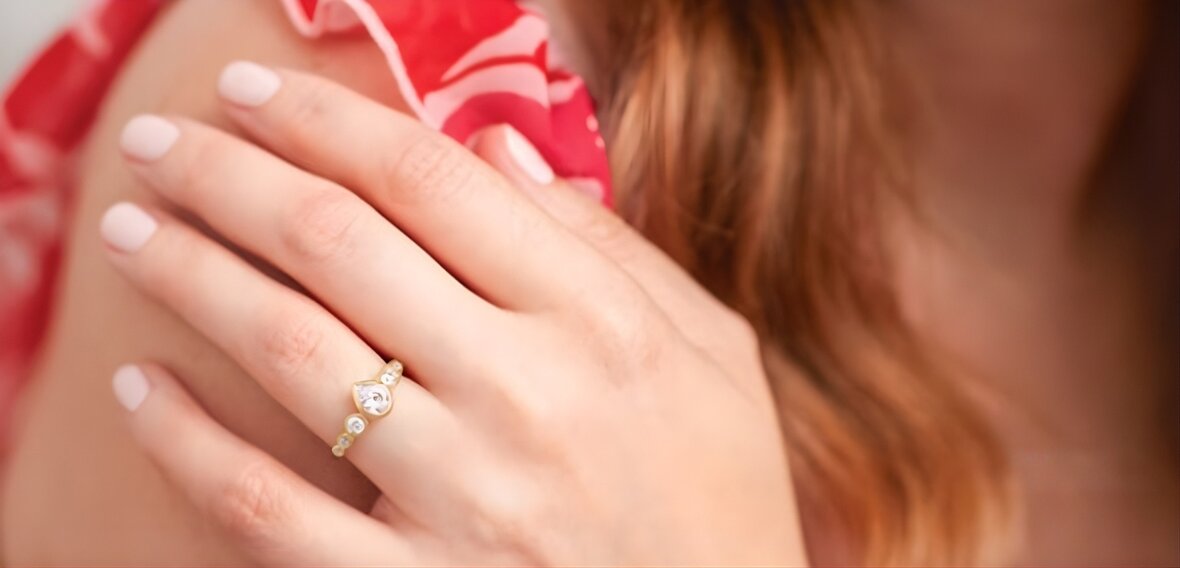 Gold solitaire engagement ring with pavé diamond band demonstrating proper ring fit on finger