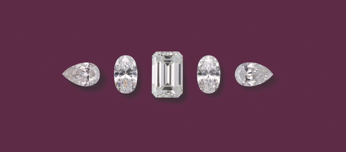 Loose diamonds showing pear, oval, and emerald cut shapes arranged on a plum background