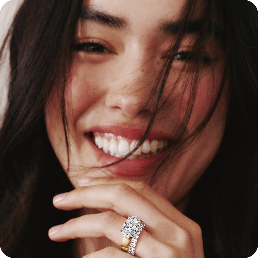 Woman in a white dress wearing jewelry outdoors against a natural background