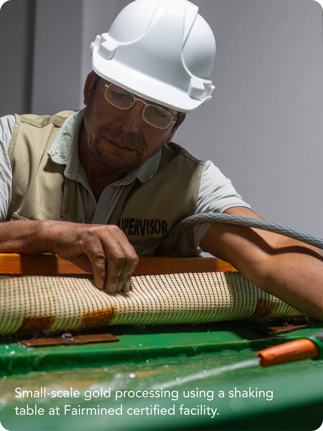 Person wearing safety equipment working at a gold processing table