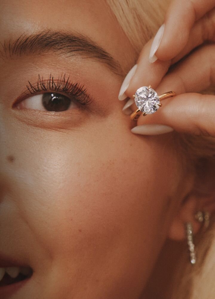 Close-up of someone's hand wearing a diamond engagement ring, emphasizing transparency and brilliance
