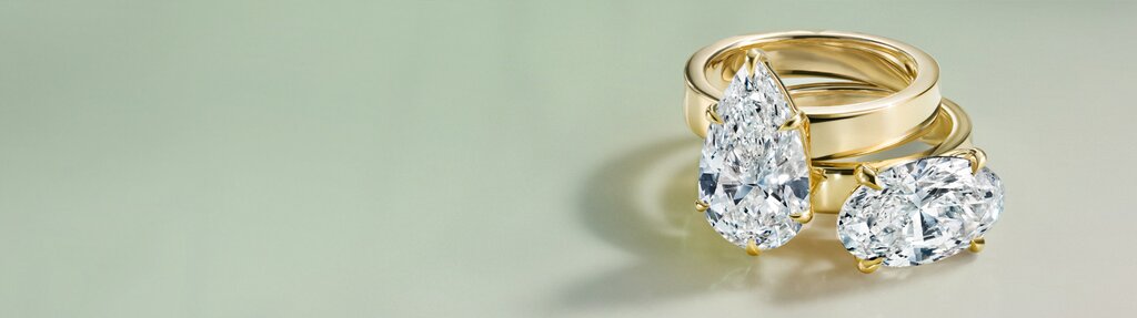 Gold diamond engagement ring against soft white gradient background