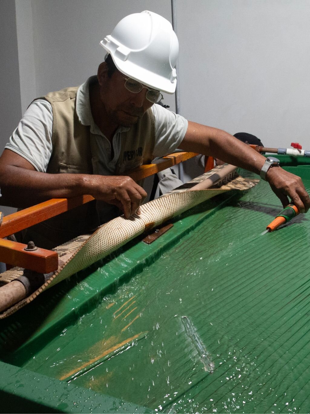 Person wearing safety equipment working at a gold processing table