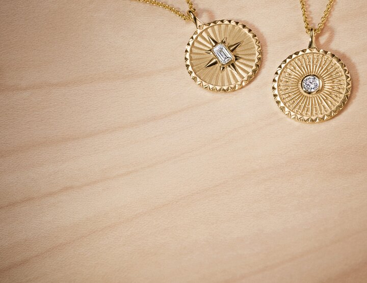 Close-up of multiple gold rings and jewelry bracelets arranged on light surface