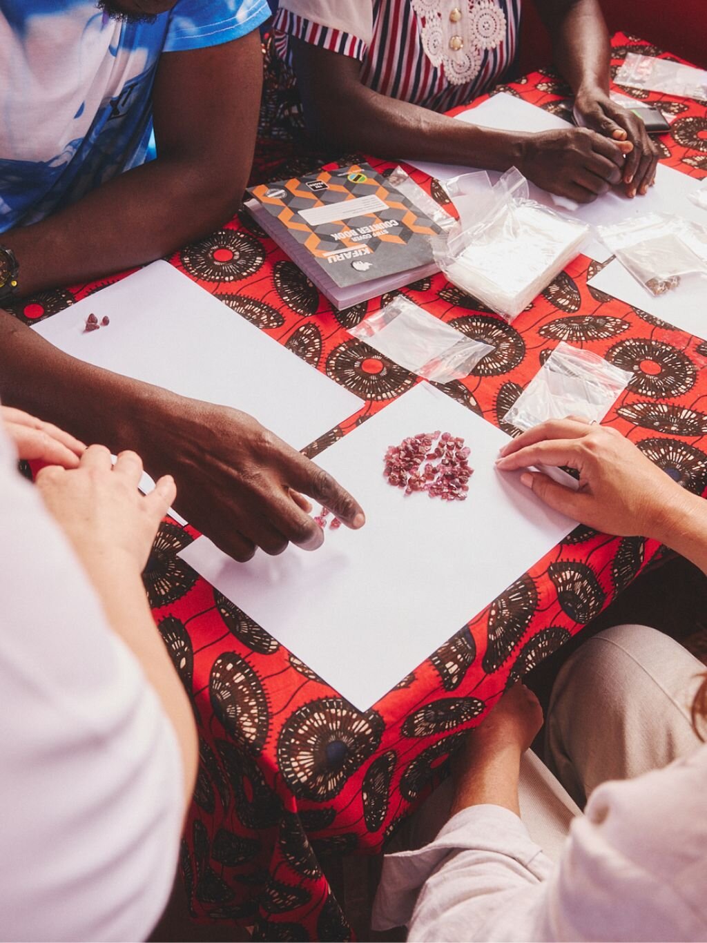 Close-up of hands sorting loose gemstones on paper