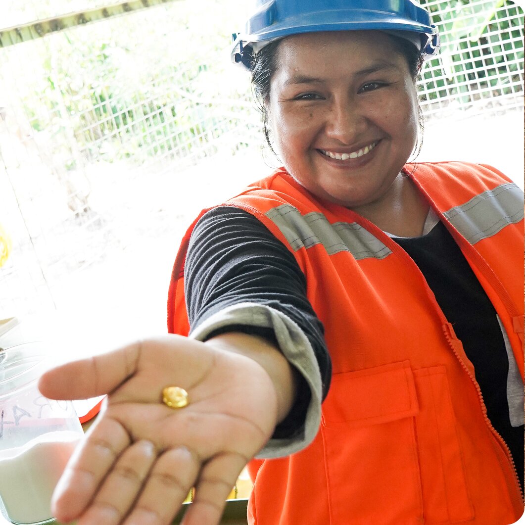 Worker in orange safety vest tending to plants in outdoor setting