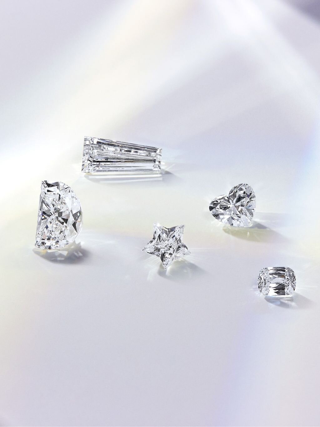 Multiple loose lab-grown diamonds displayed on a light purple or white surface