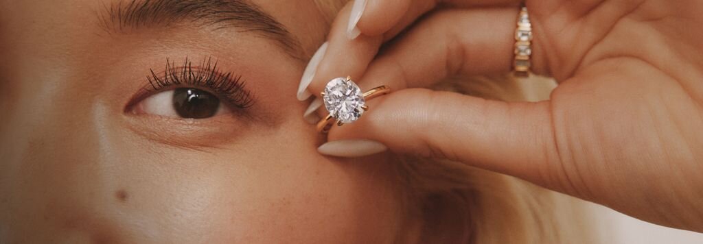 Close-up of someone's hand wearing a diamond engagement ring, emphasizing transparency and brilliance