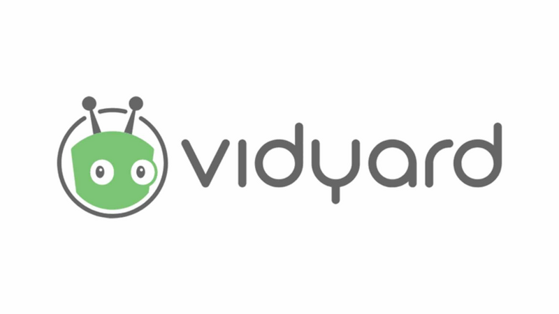 Vidyard logo featuring a green stylized robot head icon inside a circular outline, next to the word "vidyard" in a gray, rounded sans-serif typeface.