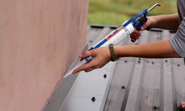 Construction worker with silicone tube making roof waterproof