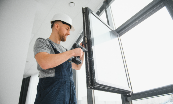 Construction worker with plastic sealant making windows weatherproofing 