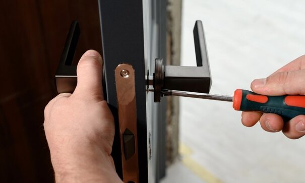 A worker installs a door handle in a door