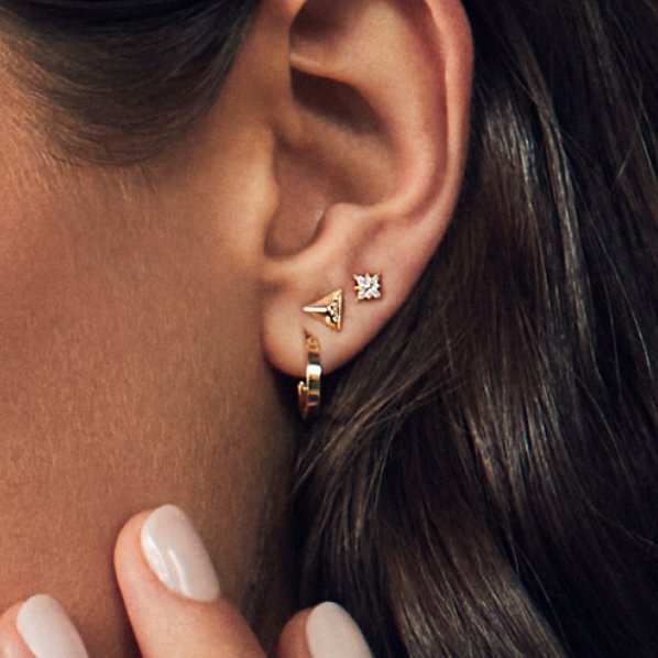 A woman wearing three fashion earrings