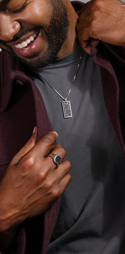 A man wearing a dog tag necklace and a fashion signet ring