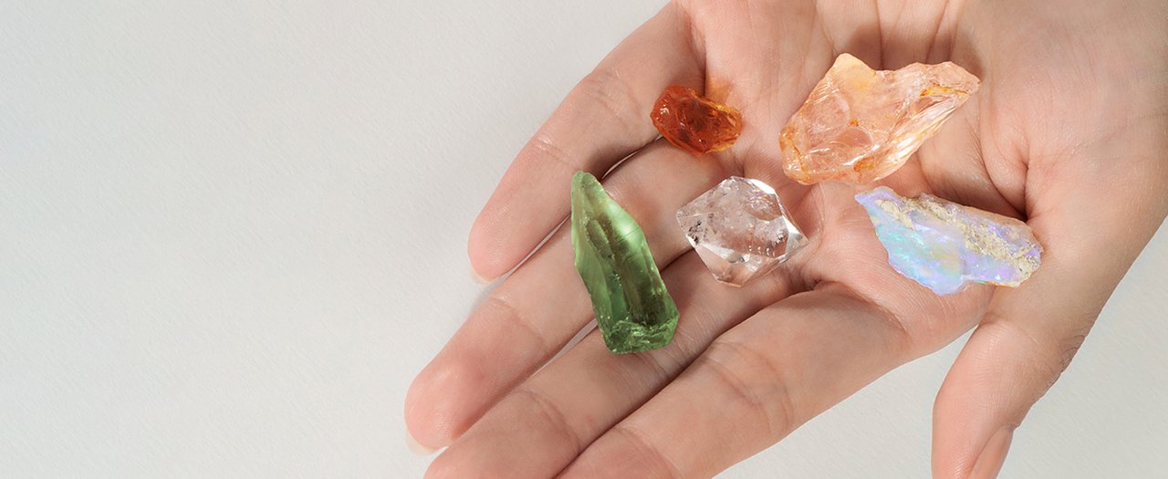 A hand holding a collection of raw gemstones