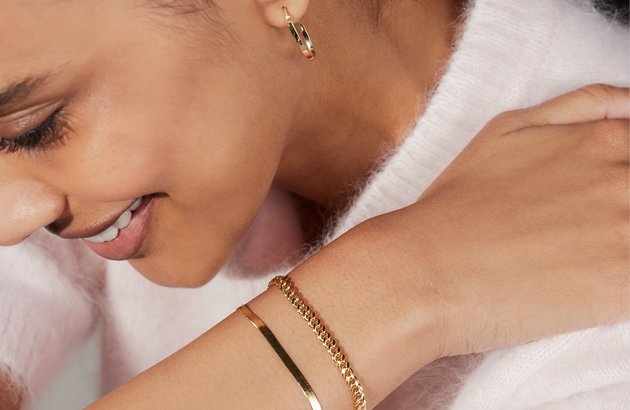 A woman wearing gold bracelets and earrings