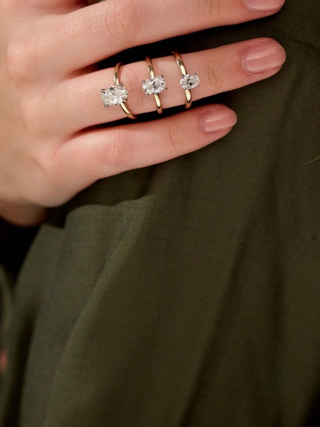 A woman's hand with three solitaire engagement rings
