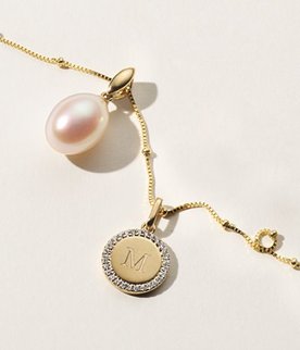 An engraved pendant and a pearl pendant on a gold chain