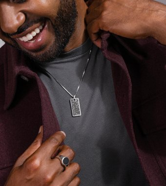 A man wearing a fashion ring and dog tag pendant