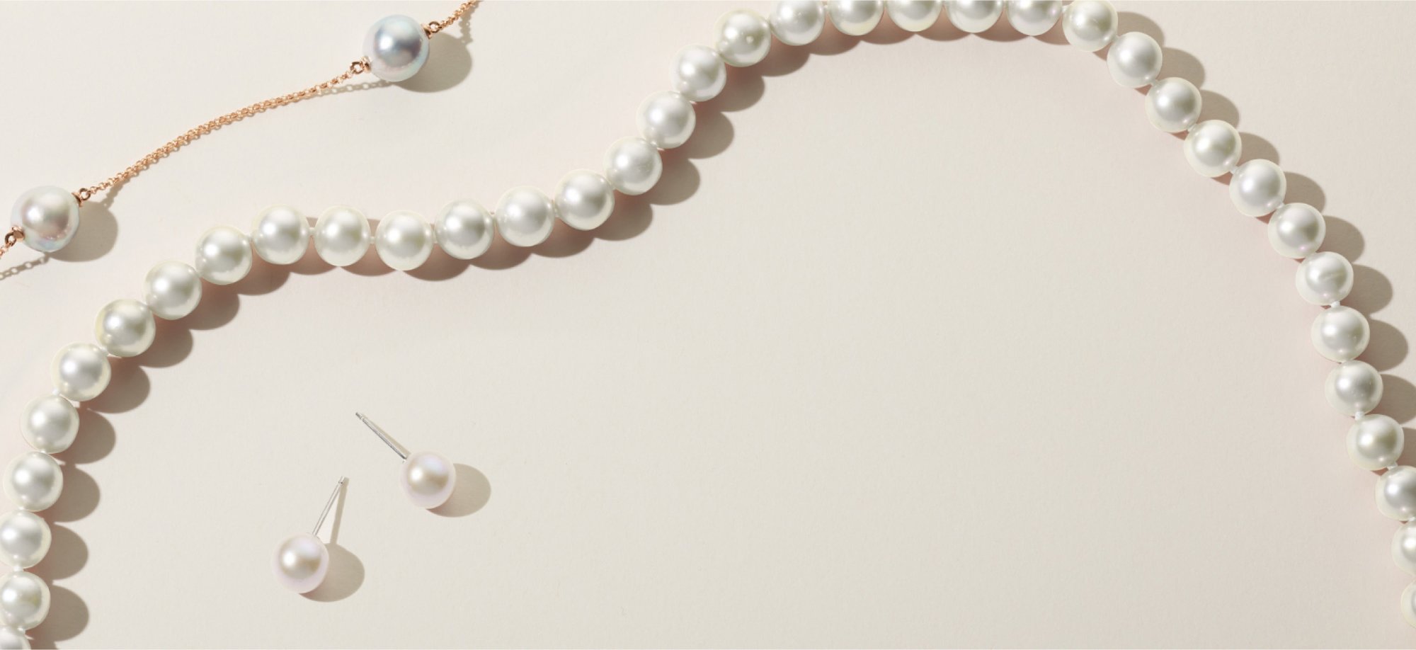 A string of pearls, a yellow chain with pearl accents, and a pair of pearl studs