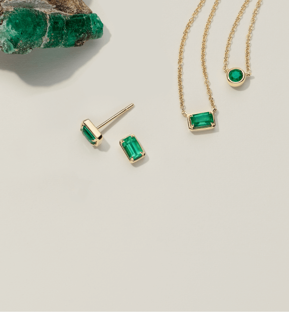 Image: A collection of emerald jewelry, featuring emerald necklaces, earrings, and an uncut emerald. The necklaces and earrings showcase brilliant green emeralds set in various designs, while an uncut emerald gemstone is also featured in its raw form.