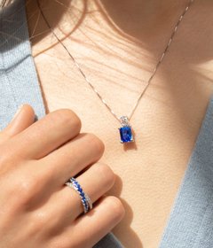 A woman wearing a gemstone fashion ring and matching pendant