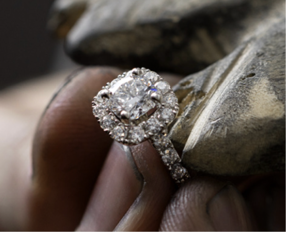 A jeweler's hands holding a diamond engagement ring