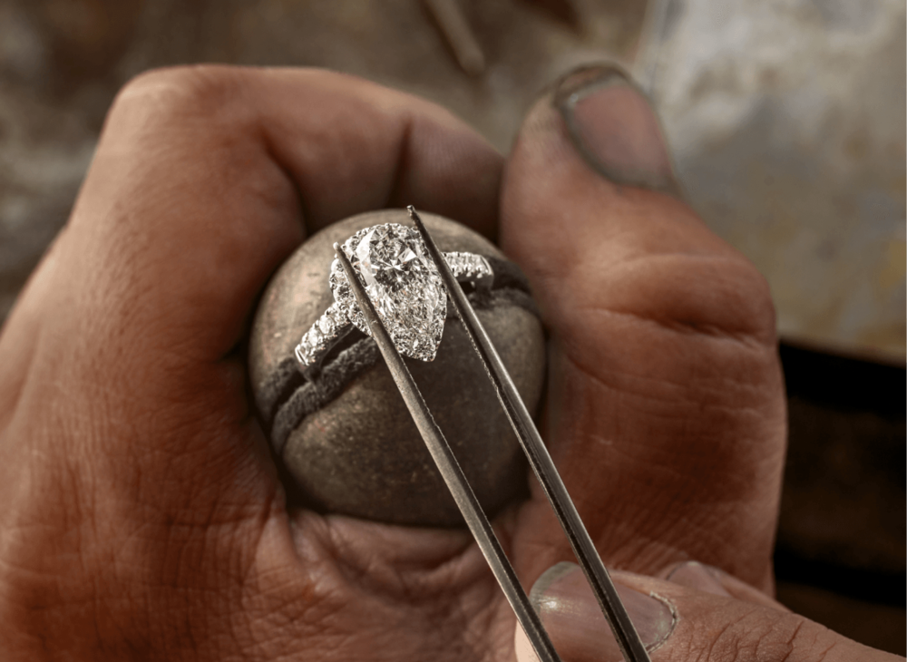 A jeweler's hands working on a diamond engagement ring