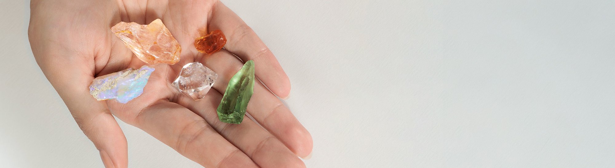 A hand holding a collection of raw gemstones