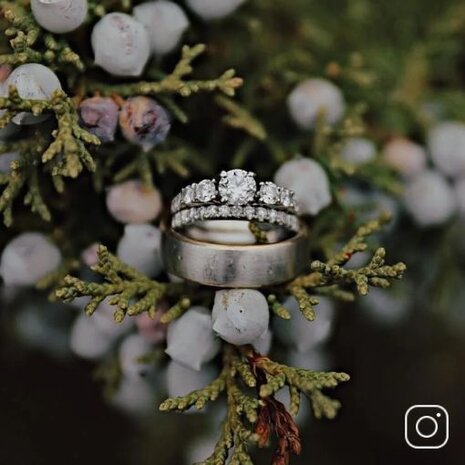 An engagement ring and wedding band stacked on top of a men's wedding band