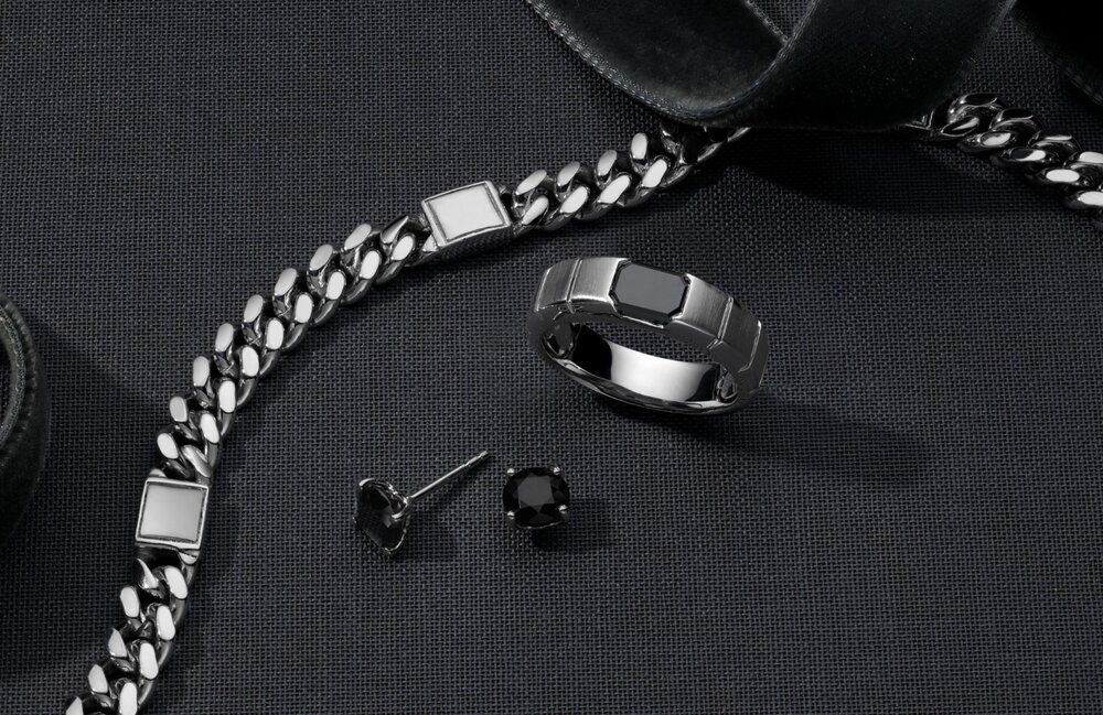 A collection of mens jewelry on a dark gray background