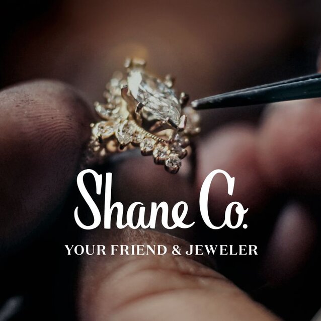 A jeweler's hand holding a diamond engagement ring