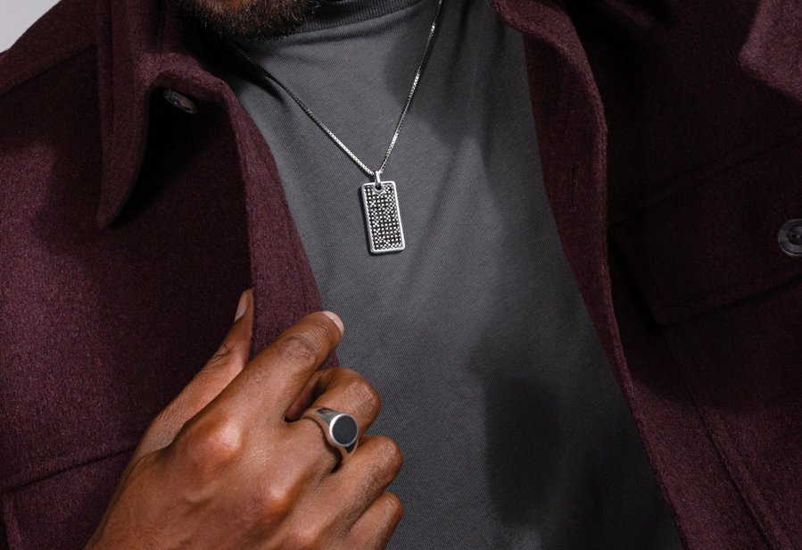 A man wearing a fashion ring and a dog tag pendant