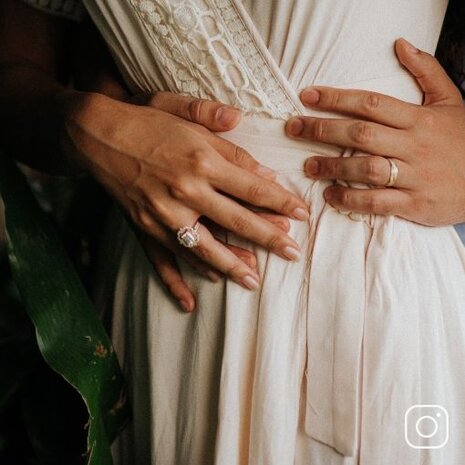 A bride and groom's hands showing their engagement rings