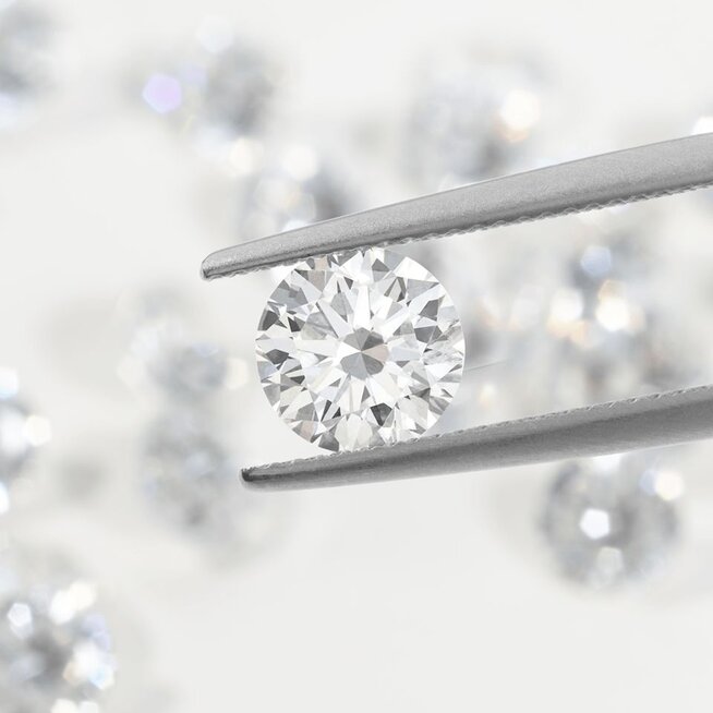 A pair of jewelers tweezers holding a loose round diamond