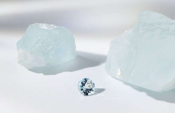 two raw aquamarine stones with a single loose aquamarine