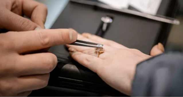 A jewelry placing a diamond into an engagement ring