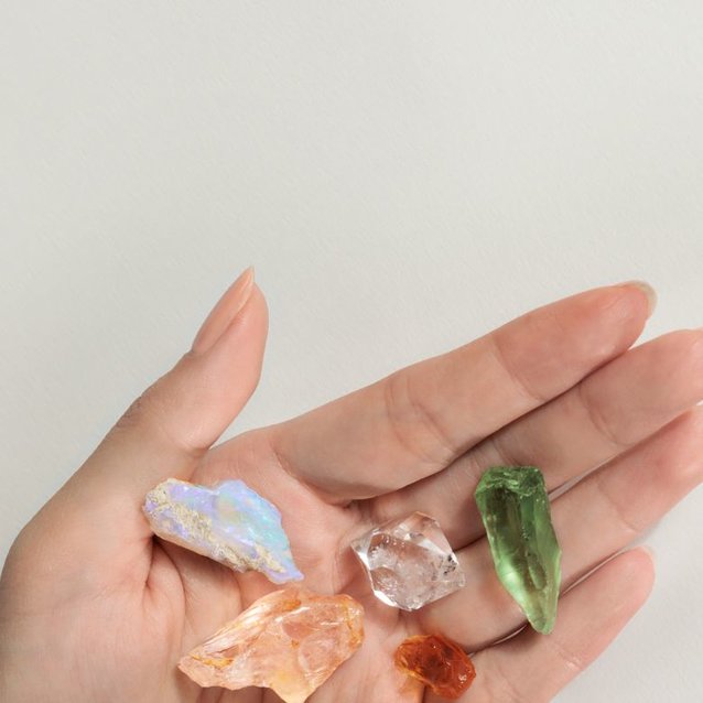 A hand holding a collection of raw gemstones