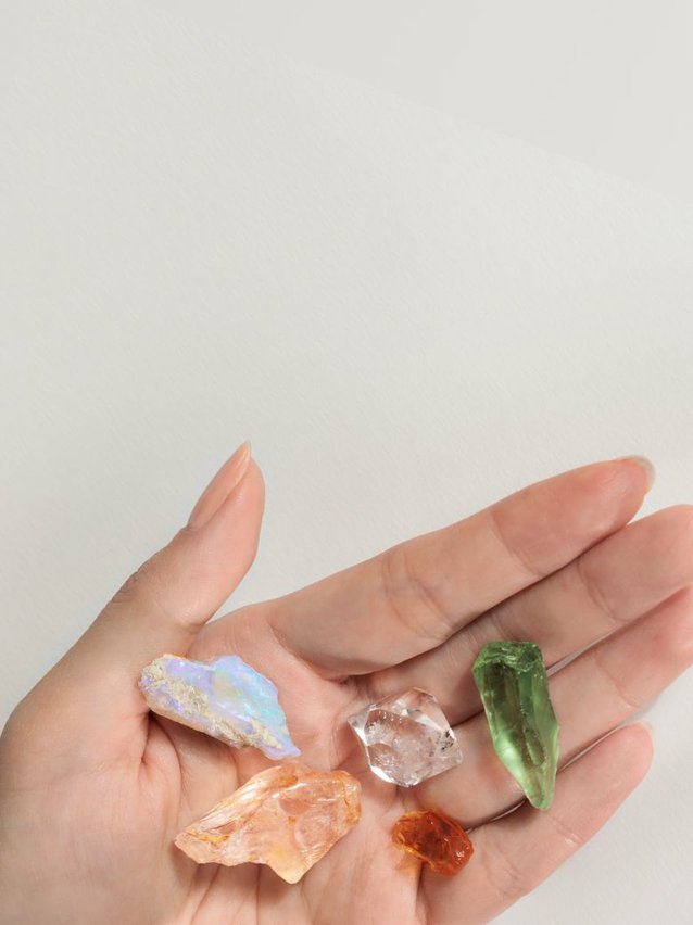 A hand holding a collection of raw gemstones