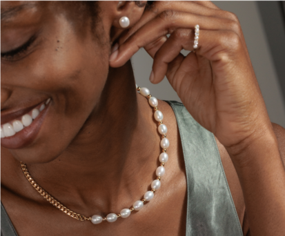 A woman wearing a pearl necklace, pearl earrings and pearl fashion ring