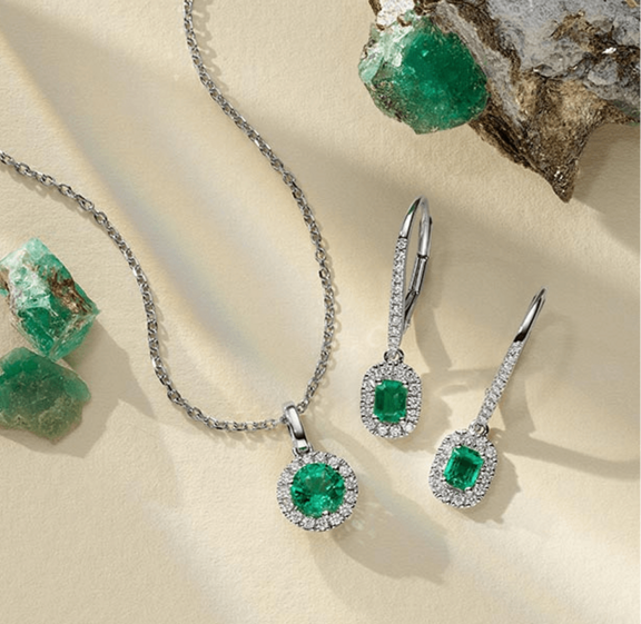 A pair of diamond and emerald earrings with a matching fashion pendant for May birthdays
