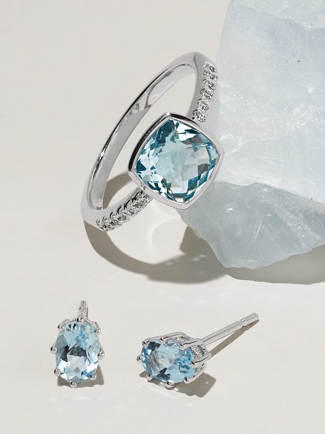 image of raw aquamarine stone with aquamarine engagement ring and aquamarine stud earrings